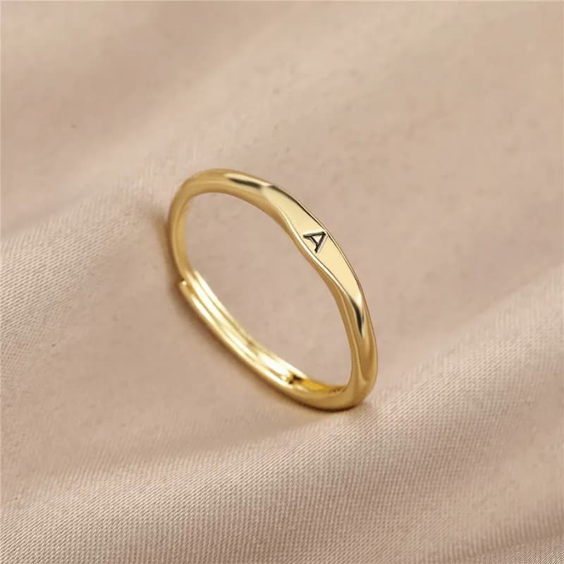 Slim gold-tone wave band ring engraved with a single initial, open adjustable fit