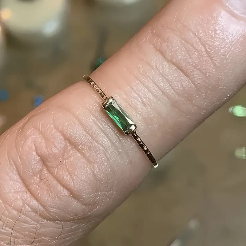 Green cubic zirconia baguette set across a slim gold-plated band with a matte texture