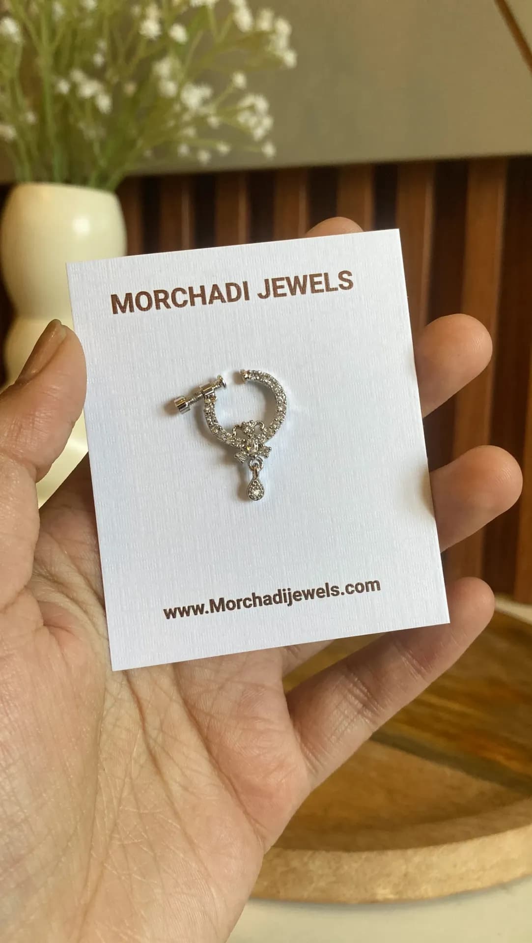 Pave-set silver-tone nose ring with a small flower at the base and a hanging teardrop